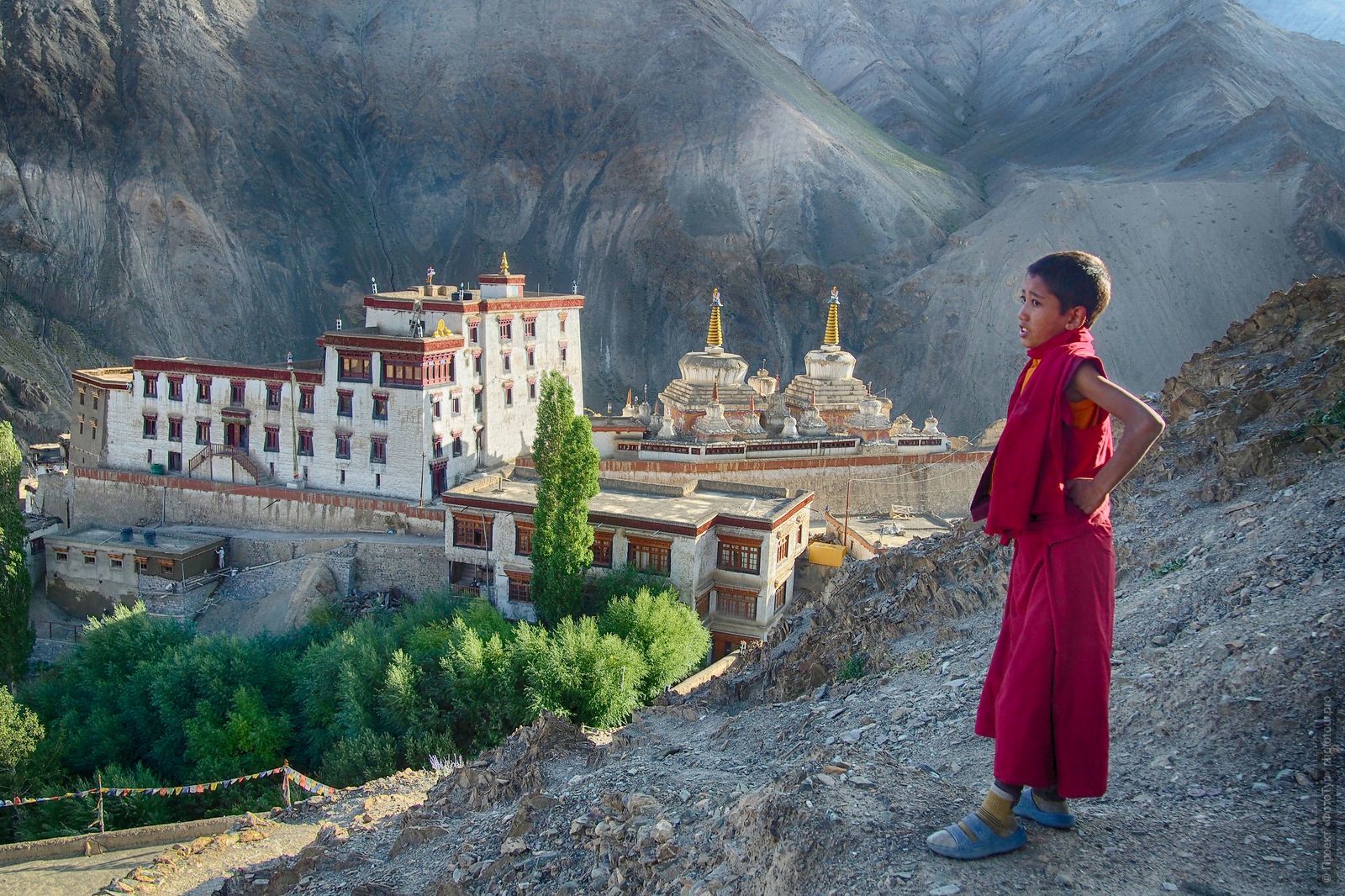 Маленький лама на фоне буддийского монастыря Ламаюру Гонпа, деревня Ламаюру, Ладакх.